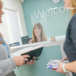 Three NHS staff talk around reception desk